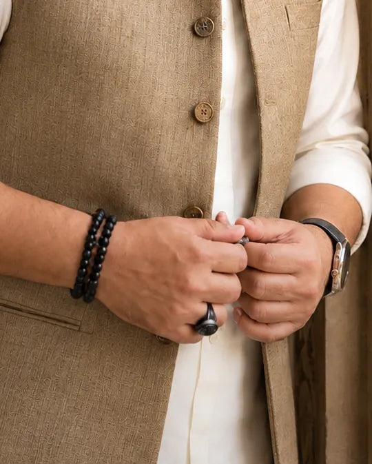 Atif's hands with a beaded bracelet, signet ring and a leather-strap watch